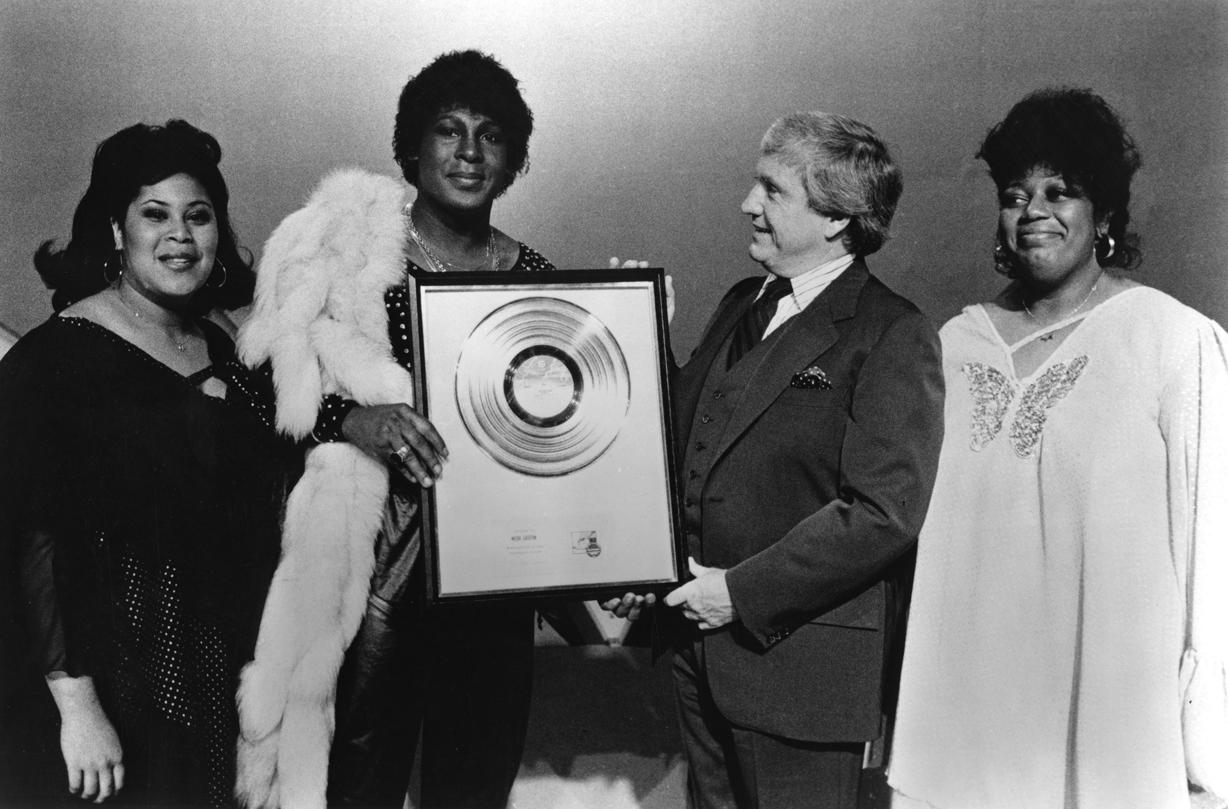 As a testament to their collective success, Sylvester, Marth Wash (left), and Izora Rhodes Armstead (right) appear together to present a gold <i>Step II</i> album to TV host Merv Griffin, Los Angeles, 1978. Photo via Michael Ochs Archives/Getty Images.